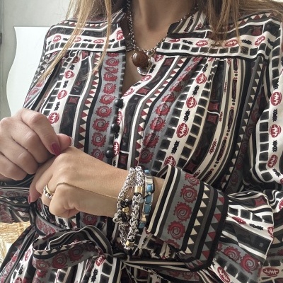 Vestido com padrão geométrico de várias cores, usado com acessórios de joalharia