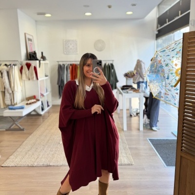 Mulher com vestido vinho e botas castanhas numa loja de roupas moderna
