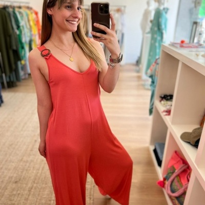 Mulher a usar macacão vermelho pantacourt com alças ajustáveis numa loja de roupas
