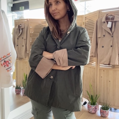Casaco impermeável verde-oliva com forro castanho e capuz usado por mulher numa loja de roupa