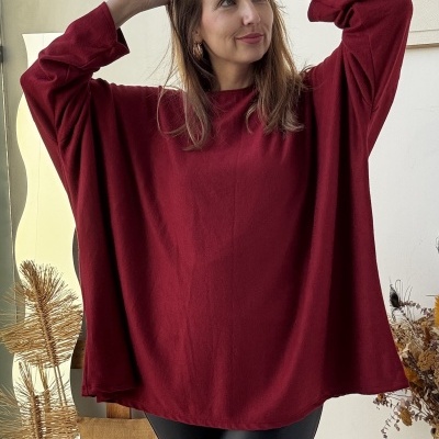 Mulher com camisa vermelha oversized e calças pretas em ambiente interior