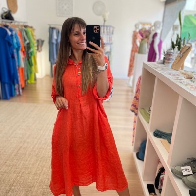 Mulher de vestido laranja midi e ténis brancos numa loja de roupas