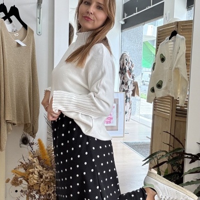 Mulher com roupa casual branca e preta numa loja de roupas