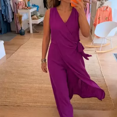 Macacão roxo comprido com laço lateral e corte cruzado usado por mulher em loja de roupas