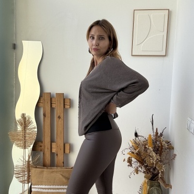 Mulher de blusa cinza escuro e leggins cinza em ambiente interior com decoração natural clara