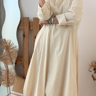 Vestido longo bege claro com barras franzidas e botas castanhas no interior minimalista