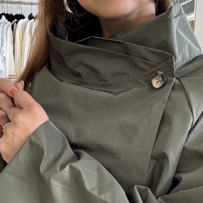 Casaco feminino verde caqui com botão no colarinho usado por mulher