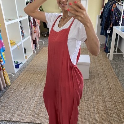 Mulher com macacão vermelho e t-shirt branca a tirar selfie com smartphone