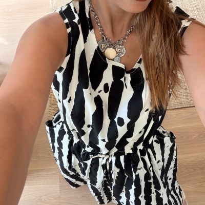Vestido preto e branco com padrão de manchas usado por mulher com colar prateado