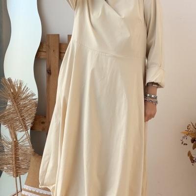 Vestido bege comprido com mangas compridas e botas castanhas em ambiente interior