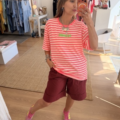 Mulher com t-shirt às riscas rosa e branco e bermuda castanha numa loja de roupa