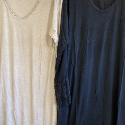 Duas túnicas em tecido macio, bege e preta, com renda nas mangas e barra.