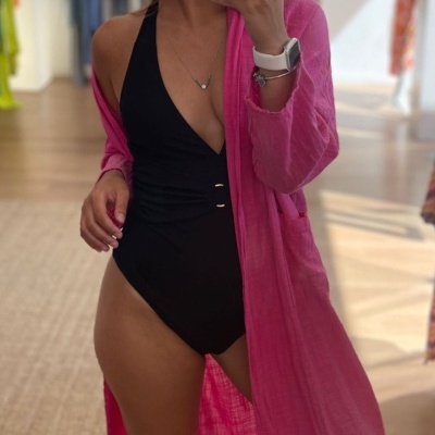 Mulher com fato de banho preto e robe rosa translúcido num espelho