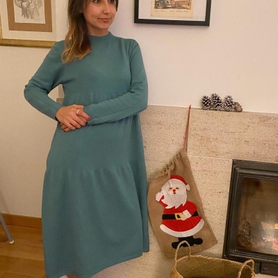 Mulher com vestido verde-água junto a lareira com decoração de Natal
