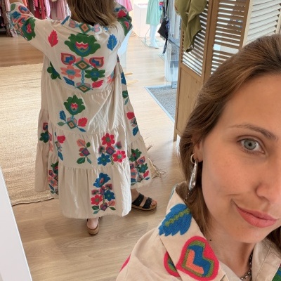 Vestido bege claro com bordados coloridos visto de costas no espelho