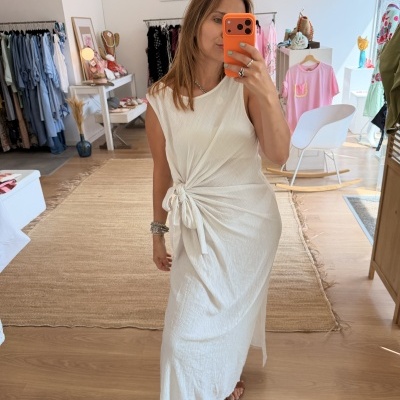 Vestido branco com nó lateral e textura leve numa loja de roupa