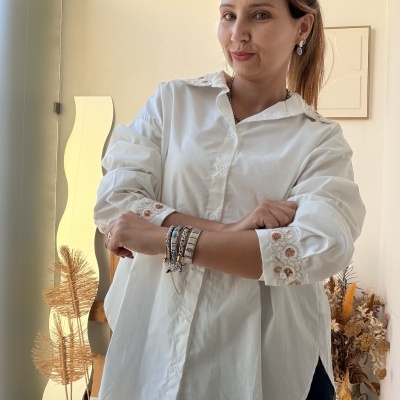 Blusa branca bordada usada por mulher com pulseiras e brincos