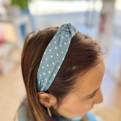 Faixa de cabelo azul claro com estrelas brancas usada por mulher