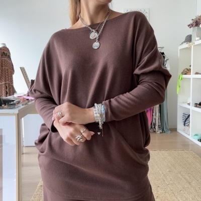 Conjunto castanho de malha com camisola larga e calças, mulher com acessórios prateados