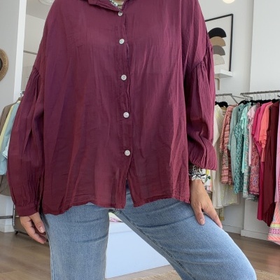 Blusa vinho com botões e jeans azuis claros em loja de roupas