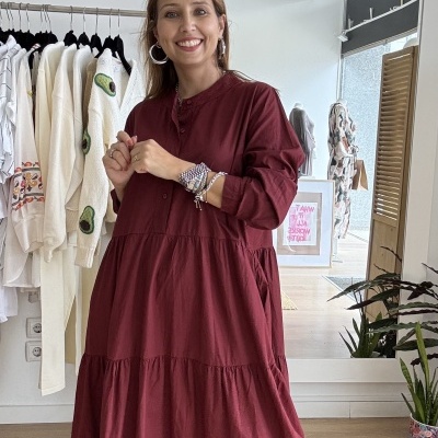 Mulher com vestido comprido vermelho vinho em loja de roupa