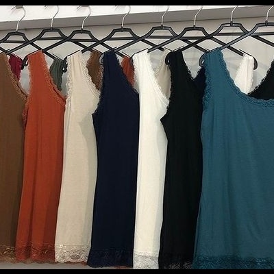 Oito blusas de alças finas com renda na barra em várias cores penduradas em cabides