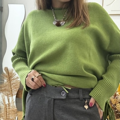 Mulher a usar camisola verde de malha e calças cinzentas