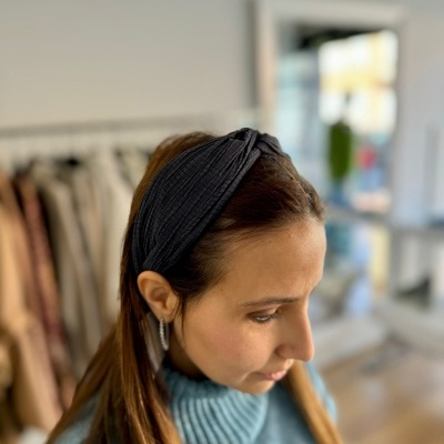 Mulher com faixa de cabelo preta e suéter azul em ambiente interno