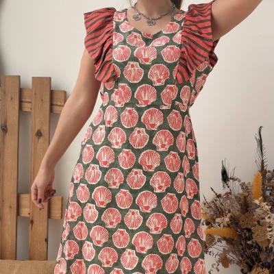 Vestido comprido com padrão conchas e folhos às riscas, modelo feminina em interior decorado.