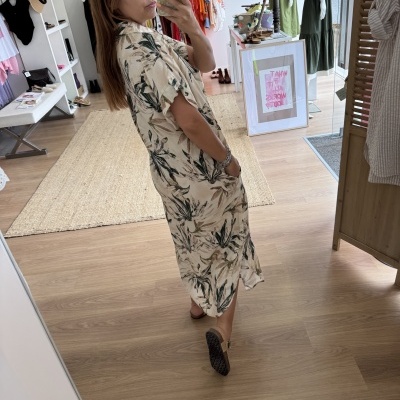 Vestido comprido bege com padrão floral verde e castanho a ser usado numa loja