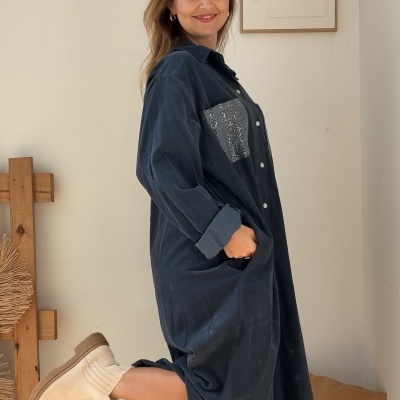 Vestido azul comprido com bolsillo de lantejoulas e botas bege em ambiente interior
