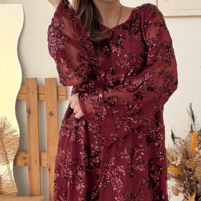 Vestido vinho com bordados brilhantes e mangas transparentes em ambiente rústico