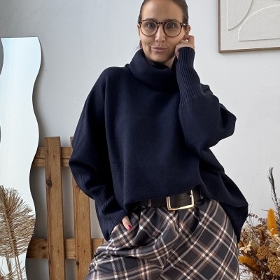 Mulher com camisola azul escura e calças xadrez castanhas em ambiente interior