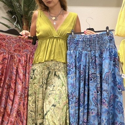 Mulher segurando duas saias compridas com padrões em tons vermelho e azul