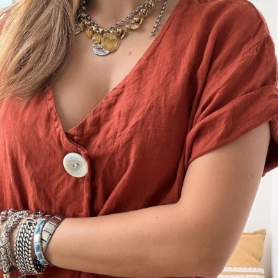 Mulher com colar, brincos, pulseiras e vestido cor ferrugem