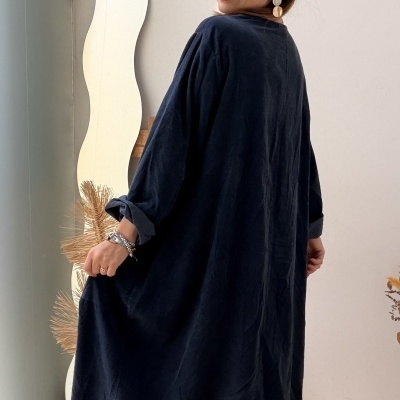 Mulher com vestido azul-escuro comprido e botas pretas em interior