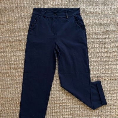 Calças de tecido azul escuro com cintura alta e barra dobrada sobre tapete bege