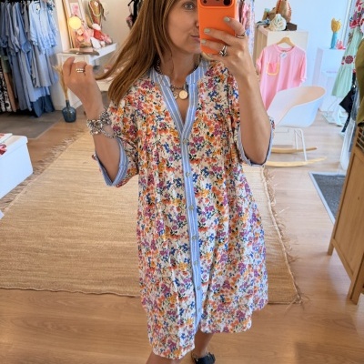 Vestido floral colorido com riscas azuis usado por mulher em loja de roupa
