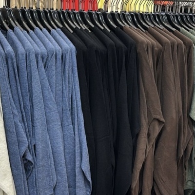 Camisolas de manga comprida em várias cores penduradas em cabides numa loja.