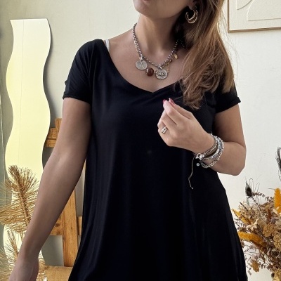 Mulher com t-shirt preta e calças pretas justas usando acessórios metálicos