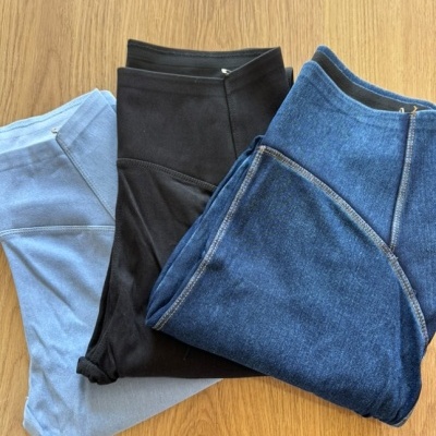 Três calças de cores diferentes dobradas sobre chão de madeira