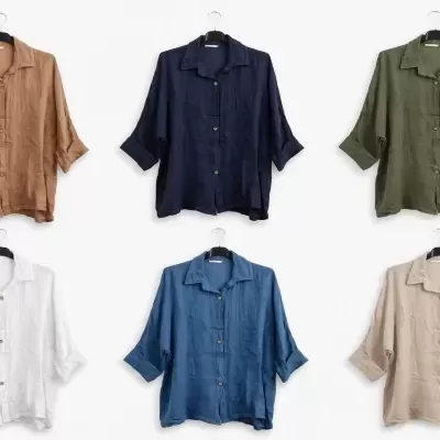 Seis camisas de linho coloridas penduradas em cabides num fundo branco