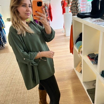 Mulher a tirar selfie na loja vestindo blusa verde e botas castanhas.