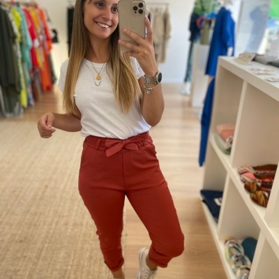 Mulher com calças vermelhas e camiseta branca em loja de roupas