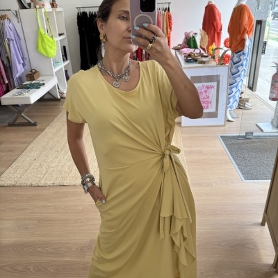 Vestido amarelo claro com nó lateral usado por mulher em loja
