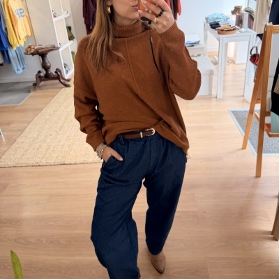 Mulher a tirar selfie com camisola castanha e calças azuis largas