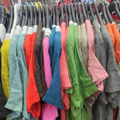 T-shirts coloridas penduradas em cabides pretos num suporte de roupa.