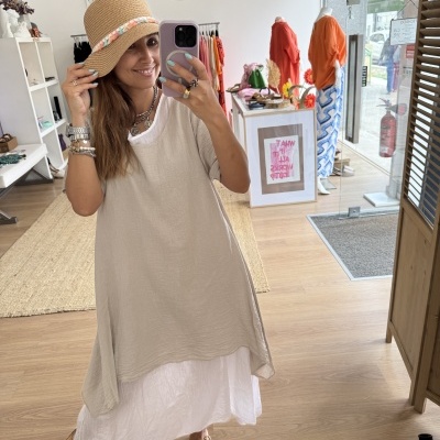 Mulher com vestido bege e chapéu de palha numa loja de roupas