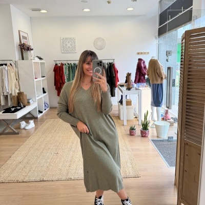 Mulher em loja de roupa com vestido verde-oliva de malha e sapatos pretos e brancos