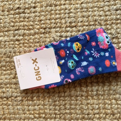 Meias decorativas azuis com caveiras coloridas e etiqueta GNC-X